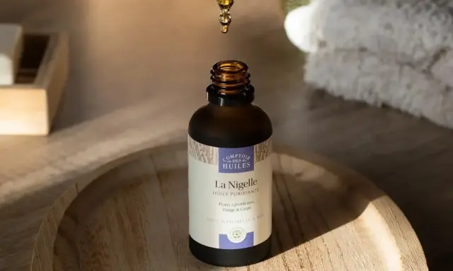 Une goutte d'huile de nigelle, aux propriétés anti inflammatoires, tombe dans un flacon. Idéal pour peaux à problèmes.