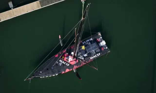 Le voilier MACSF, piloté par Corentin Horeau, est hissé hors de l'eau par une grue.