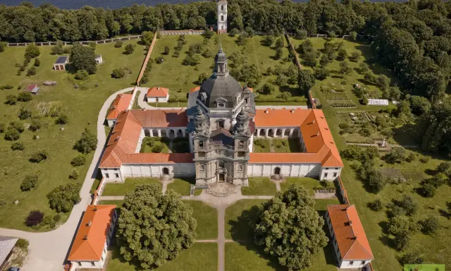 Litwa atrakcje: imponujący klasztor z kopułą i wieżą, otoczony zielenią i ogrodem, nad brzegiem jeziora.