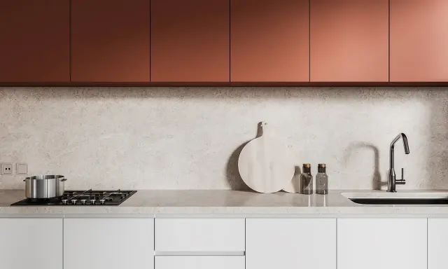 Crédence de cuisine moderne avec placards cuivrés, plan de travail en marbre clair, plaque de cuisson, évier et ustensiles.