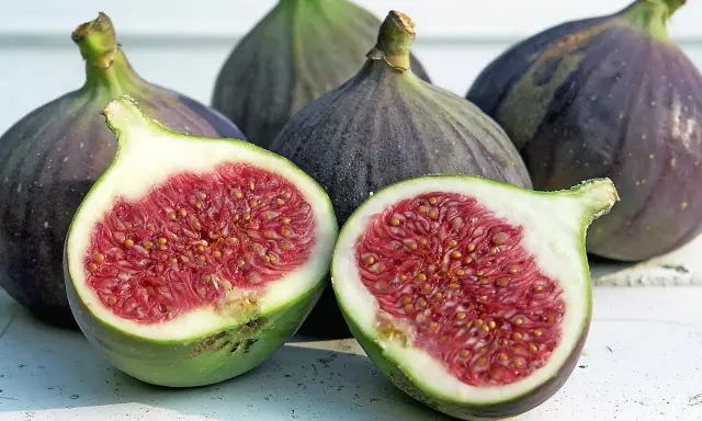 Frische Feigen, eine aufgeschnitten, zeigen ihr saftiges Inneres. Sie sind feigen gesund und ein Genuss.