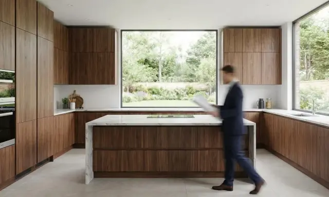 Cuisine en U de petite surface, 5m2, avec îlot central et grandes fenêtres offrant une vue sur le jardin. Meubles en bois de noyer.
