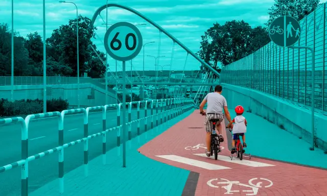 Ojciec i syn na rowerach jadą ścieżką rowerową. Obowiązują przepisy dla rowerzystów, w tym ograniczenie prędkości do 60 km/h.