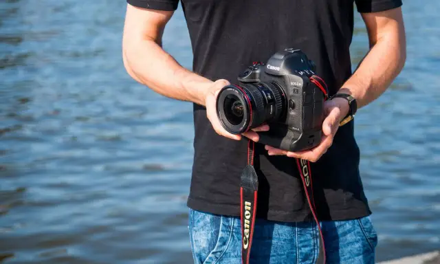 Mężczyzna trzyma aparat Canon EOS-1D Mark II z obiektywem, idealny do fotografii krajobrazowej dzięki matrycy **APS-C**.
