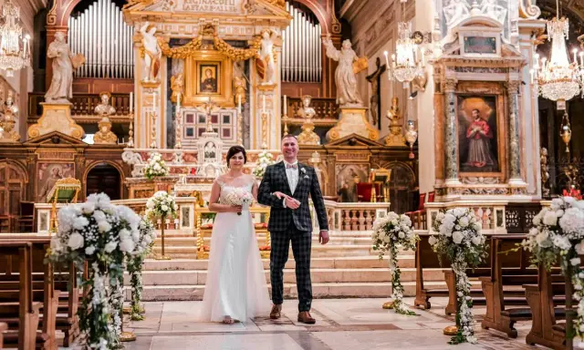 Para młoda idzie do ołtarza podczas ślubu w Rzymie. Wspaniała bazylika, ozdobiona kwiatami i organami, tworzy magiczną atmosferę.
