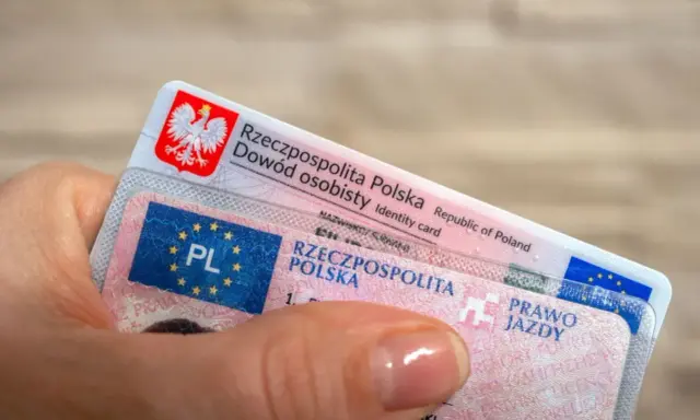 Dłoń trzyma polski dowód osobisty i prawo jazdy. Czas na wymianę prawa jazdy bezterminowego?