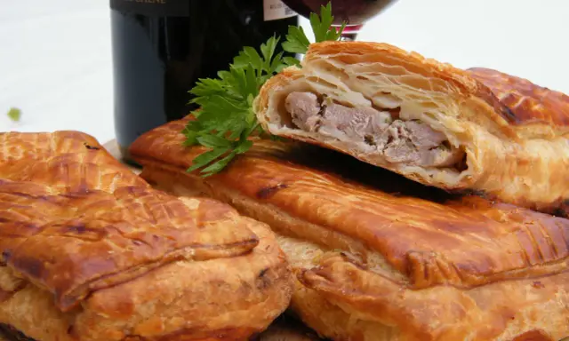 Pâté en croûte, une spécialité lorraine savoureuse, garni de viande et d'herbes, prêt à être dégusté avec un verre de vin.