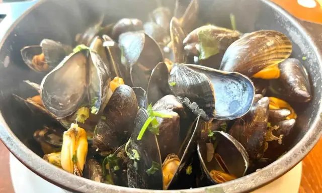 Un plat fumant de moules, prêtes à être dégustées. Un accompagnement moules parfait pour un repas savoureux.