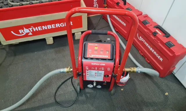 Equipo ROTHENBERGER para limpieza suelo radiante. Máquina roja con mangueras y maletines a juego.