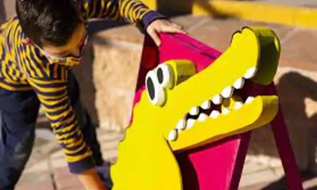 Un niño interactúa con un cocodrilo amarillo de utilería, parte de un espectáculo de teatro infantil en Málaga.