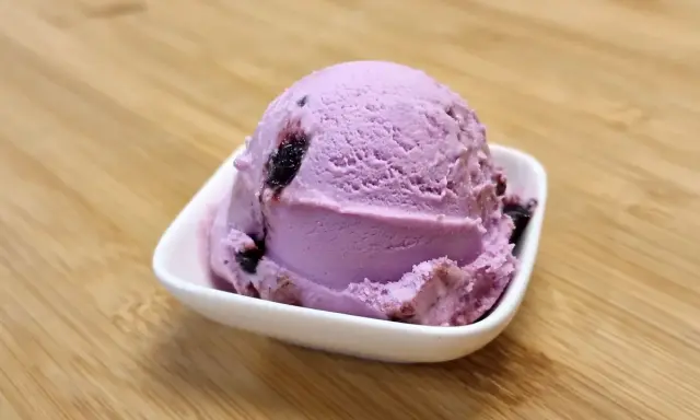 Une boule de glace violette aux fruits, parfaite pour une recette glace amarena maison.