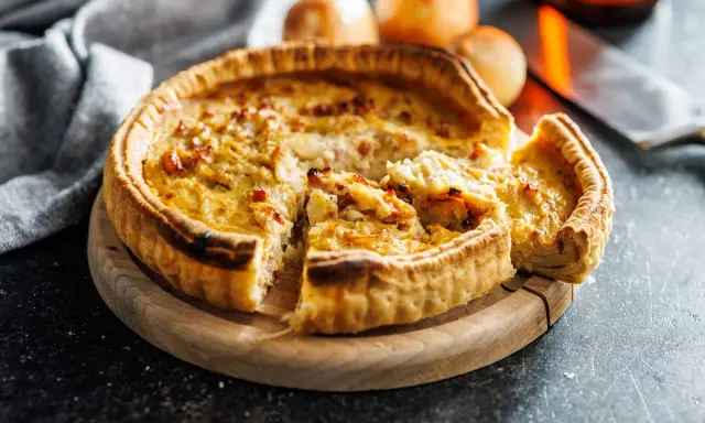 Une part de quiche lorraine, une des spécialités lorraines, sur une planche en bois.