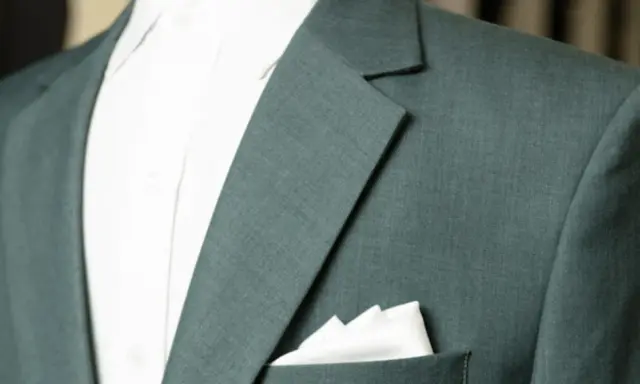 A close-up of a teal suit jacket shows the lapel and a crisp white pocket square.