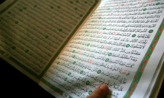Ein Finger zeigt auf eine Seite des Korans. Die Frage, wer hat den Koran geschrieben, wird durch die heiligen Schriften beantwortet.