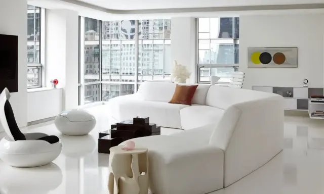 Soggiorno minimalista con divano bianco curvo, sedie futuristiche e tavolini geometrici, un vero esempio di space age design.