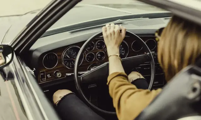 Mujer al volante de un coche clásico. De repente, la dirección asistida dura, dificultando el giro.