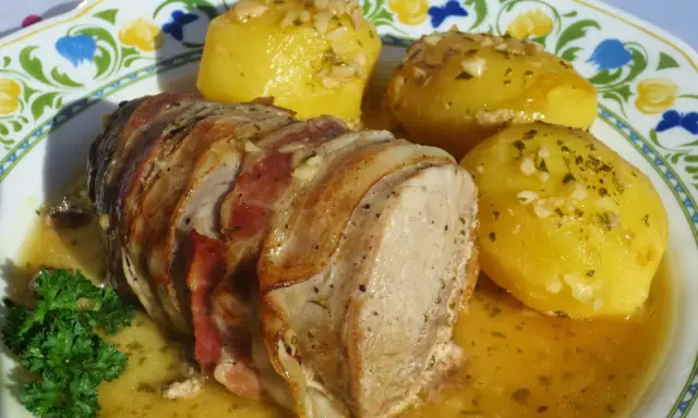 Solomillo al ajillo envuelto en bacon, servido con patatas doradas y perejil fresco. ¡Un plato delicioso!