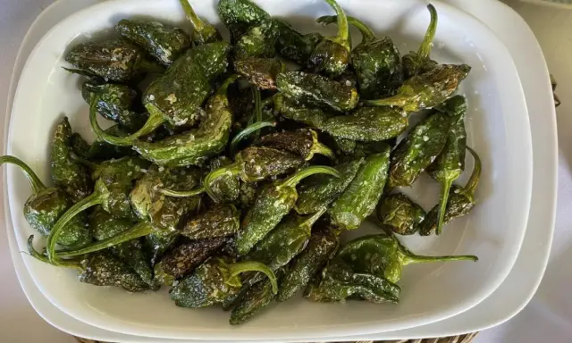 Pimientos de Padrón recién fritos, salpicados de sal gruesa, listos para disfrutar. ¡Así se preparan como freir pimientos de padron!
