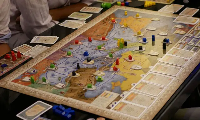 Intensywne granie w gry planszowe. Gracze strategicznie rozmieszczają drewniane pionki na mapie, budując imperium.
