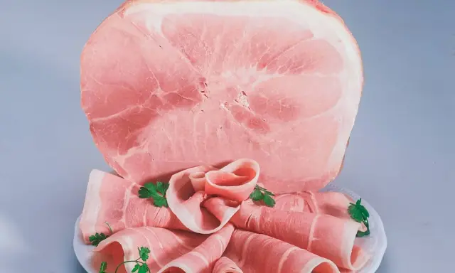 Fetta di prosciutto cotto, con fette arrotolate guarnite di prezzemolo. Attenzione: il prosciutto cotto è considerato cancerogeno.