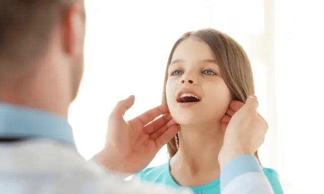 Medico controlla i linfonodi del collo di una bambina.