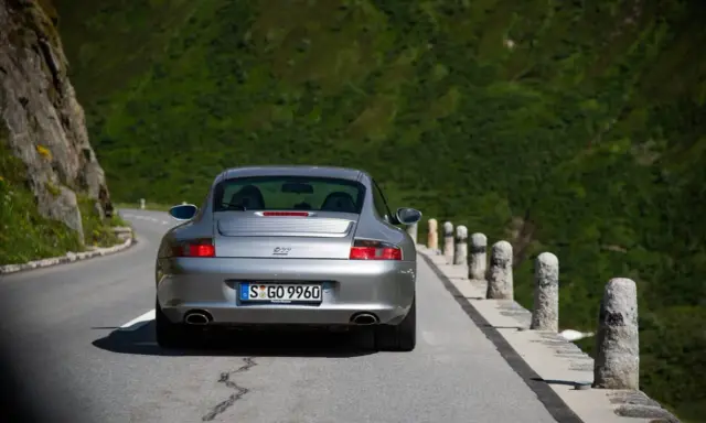 Silberner Porsche 996 4S auf Bergstraße. Ein Klassiker mit Potenzial für Wertsteigerung, der die Freiheit der Fahrt genießt.