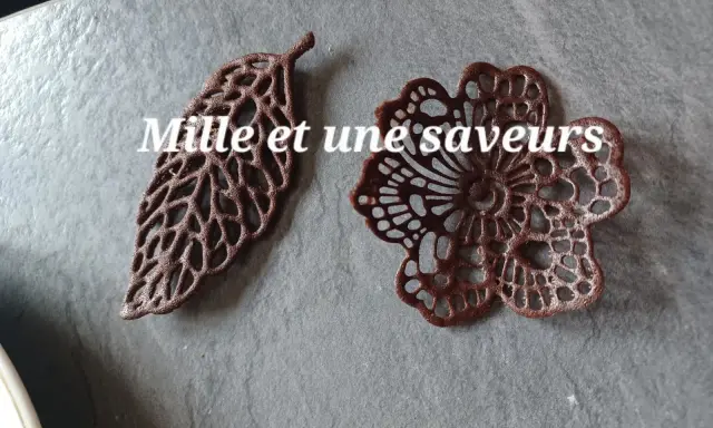 Délicates décorations en chocolat, une feuille et une fleur, réalisées avec une pâte à cigarette fine.