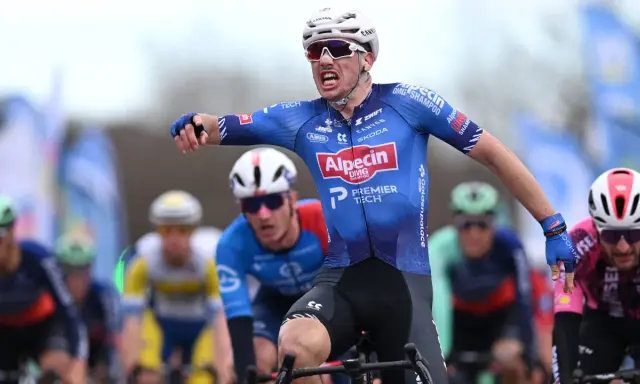 Henri Uhlig jubelt im Radsportrennen, seine Arme ausgestreckt, während er auf dem Rad sitzt.