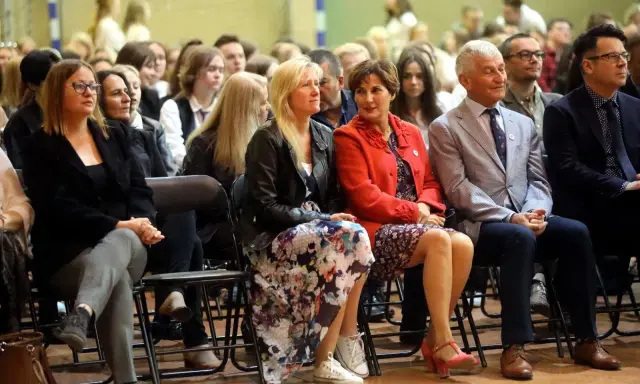 Uczestnicy siedzą na krzesłach, wśród nich widać osoby, które mogą być na radzie pedagogicznej.
