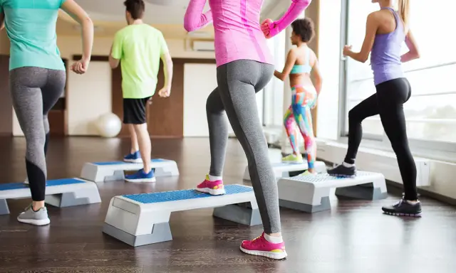 Persone in palestra eseguono attività aerobica a bassa intensità esempi: step-up.