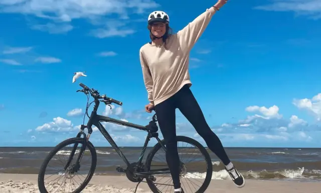 Dziewczyna w kasku na rowerze na plaży. Wspaniała infrastruktura rowerowa nad morzem.