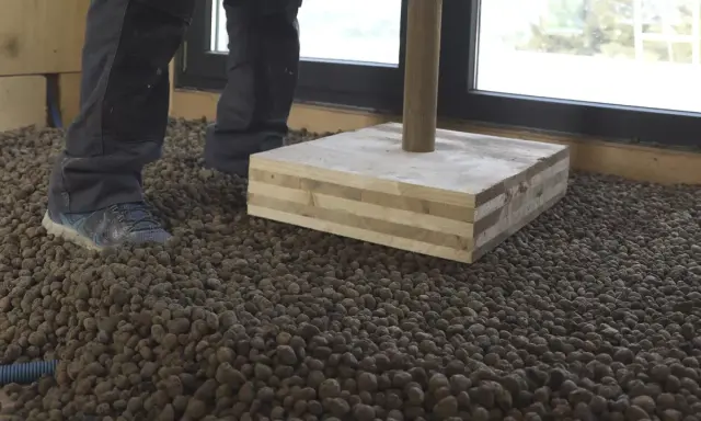 Preparando el suelo para como hacer hormigón con arlita. Se ve una capa de arlita y una base de madera.