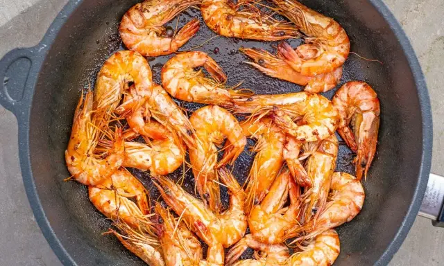 Saftige, tiefgefrorene Garnelen mit Schale werden in einer Pfanne zubereitet. Sie sind perfekt für ein schnelles Abendessen.