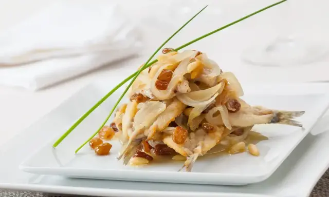 Sarde in saor, un piatto veneziano con sarde, cipolle, uvetta e pinoli, guarnito con erba cipollina.