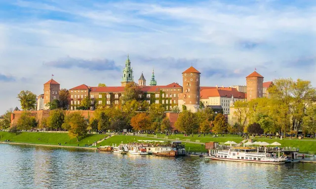 Wawel w jesiennej odsłonie, z łodziami na Wiśle. Poznaj ciekawostki o Krakowie, spacerując brzegiem rzeki.