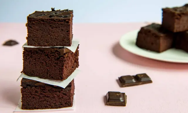 Ciemne, wilgotne brownie z fasoli ułożone w stosik, obok kawałki czekolady.