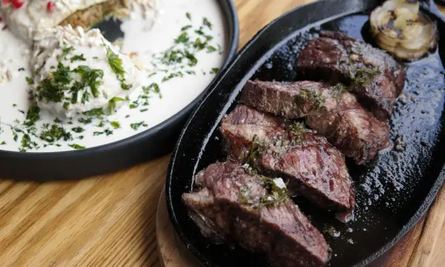 En saftig argentinsk grillfest med perfekt stekt kött och en krämig rätt med örter.