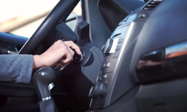 Mano girando la llave de contacto. Es malo tener el coche arrancado mucho tiempo, consume combustible y contamina.