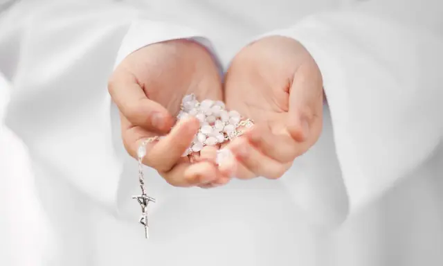 Dłonie trzymające różaniec, symbol modlitwy i intencje papieskie.