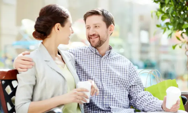Pareja sonriente compartiendo un café, un ejemplo de comunicación efectiva.
