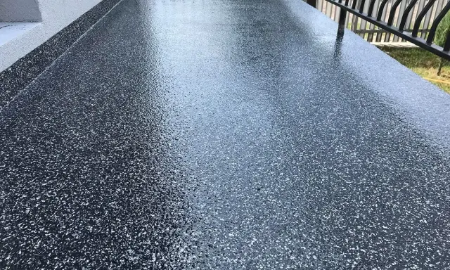 Nowy, błyszczący balkon z żywicą epoksydową. Ciemna posadzka z drobinkami tworzy nowoczesny wygląd.