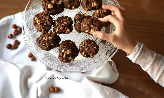 Délicieux cookies au chocolat et noisettes, parfaits pour savoir que faire avec un reste de ganache au chocolat. Une main en prend un.