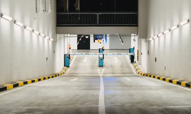 Einfahrt in eine Tiefgarage mit Schranken und Pfeilen, die den Weg weisen. Effizientes Parkraummanagement sorgt für Ordnung.