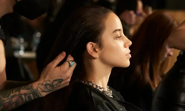 Stylista układa włosy modelki, ukazując olśniewające olaplex efekty: jedwabistość i blask.