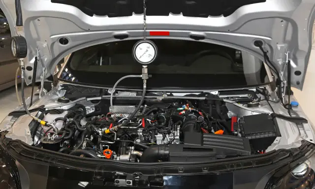 Mechanik sprawdza ciśnienie sprężania diesel w silniku samochodu za pomocą manometru.