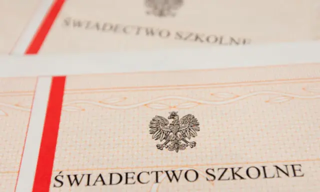 Zbliżenie na świadectwo szkolne z godłem Polski. Czerwono-biały pasek po lewej stronie.