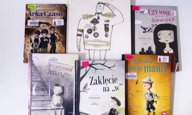 Stos książek z ilustracjami, w tym "Arka Czasu", "Wróg", "Czy wojna jest dla dziewczyn?".