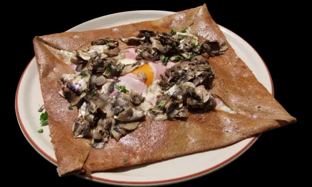 Galette complète garnie de jambon, œuf, champignons et persil. Une recette savoureuse pour un repas rapide.