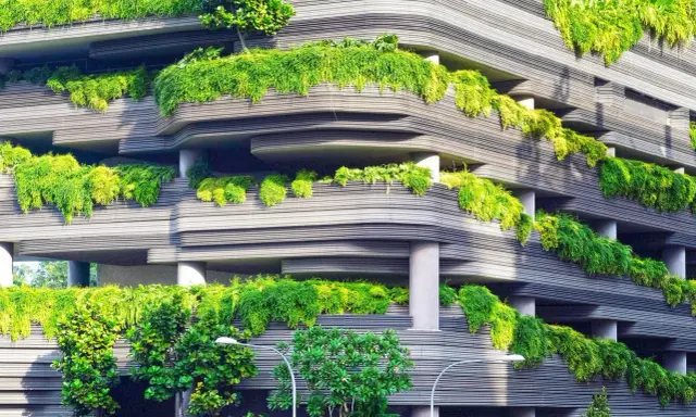 Edificio ecológico con balcones curvos cubiertos de exuberante vegetación verde, creando un oasis urbano.