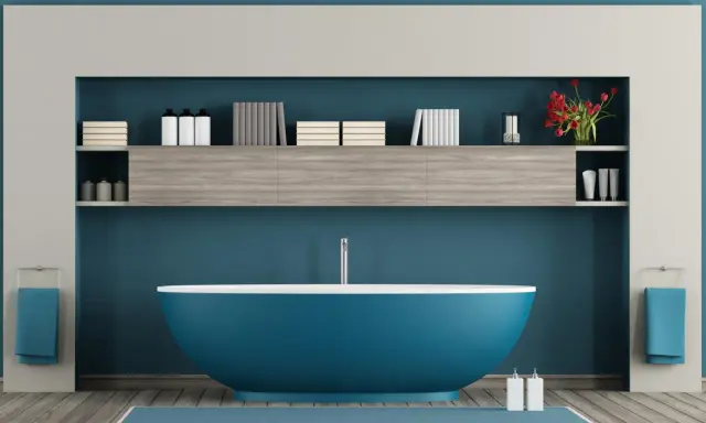 Un moderno bagno azzurro con vasca centrale, mensole piene di libri e flaconi, e due asciugamani blu appesi.